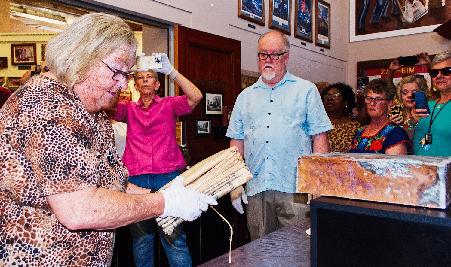 Mineola Mayor Jayne Lankford removes the contents of a copper box that was placed in the cornerstone of the new U.S. post office in Mineola in 1936 as Joyce Williams records the moment and Jimmy Phillips prepares to examine the documents Saturday.